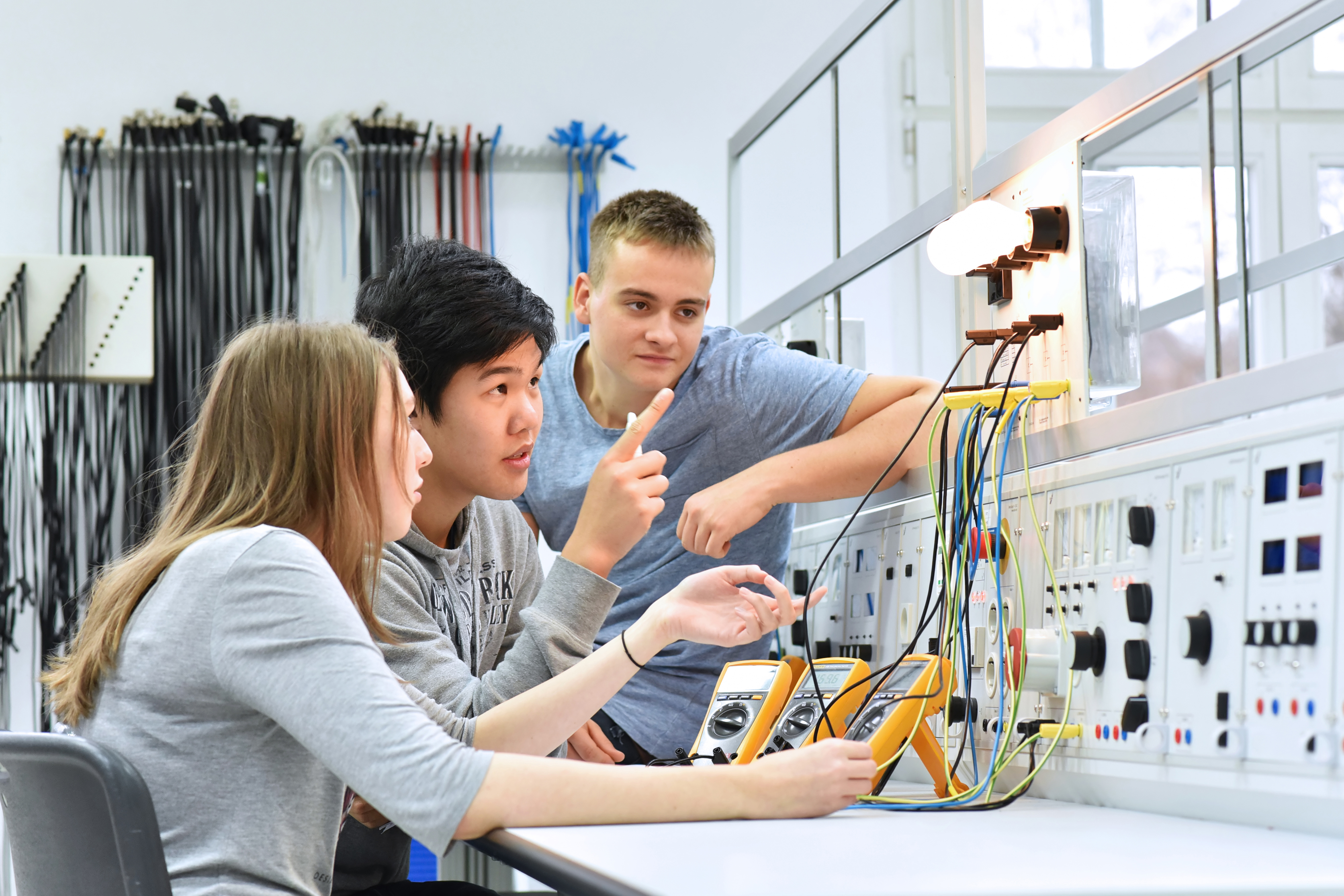 Kids operate electrical equipment in lab setting.