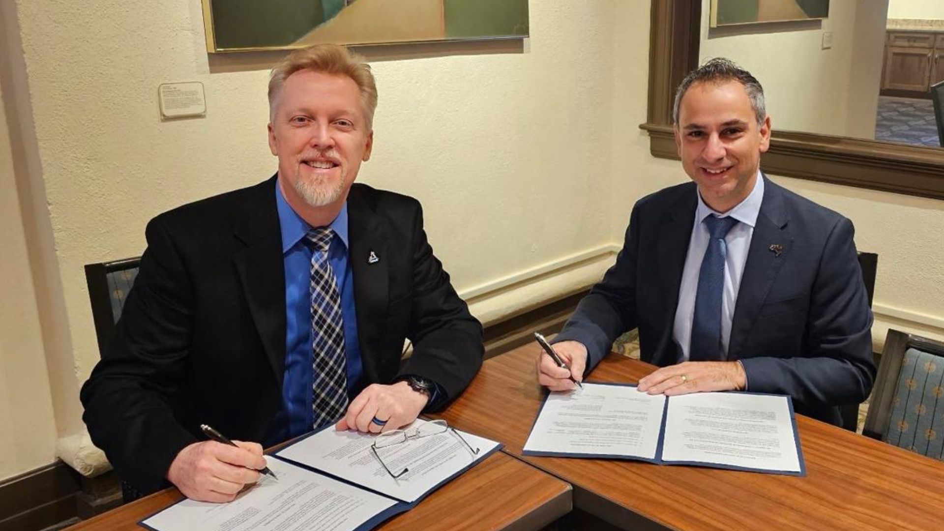 Two people posing after signing an agreement.