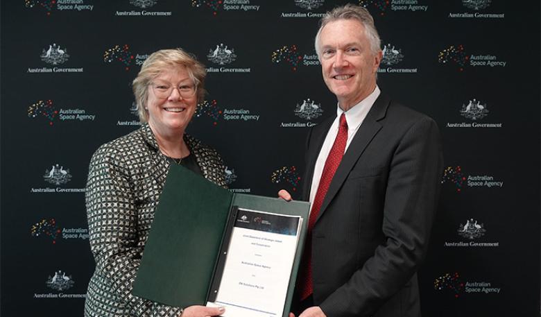 Photo of Australian Space Agency and EM Solutions leaders holding the signed agreement.