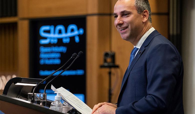 Enrico Palermo at a lectern holding his speech and smiling at the audience. The Space Industry Association of Australia’s (SIAA) logo is on a digital board in the background.