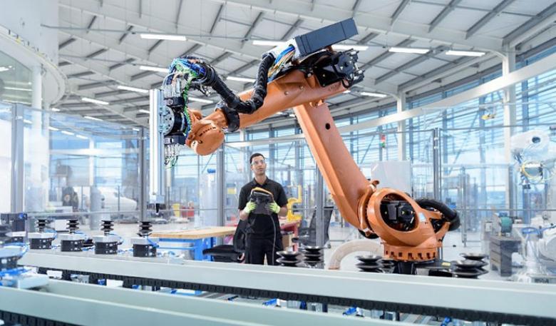 Man in factory working with large hi-tech robotics machine.