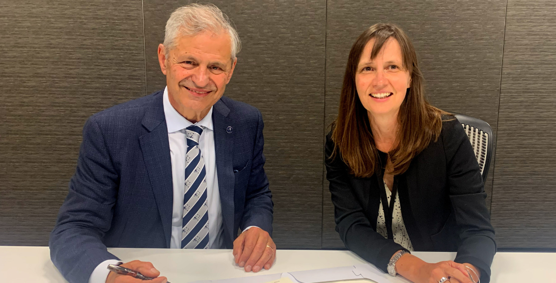 Two people posing after signing an agreement.