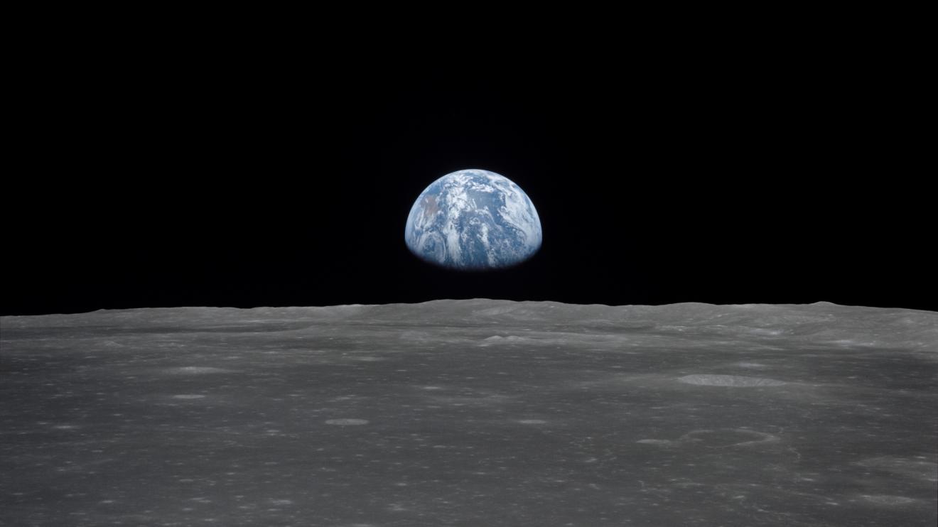 View from the Apollo 11 spacecraft shows the Earth and Australia rising above the Moon's horizon. The lunar terrain pictured is in the area of Smyths Sea on the nearside.