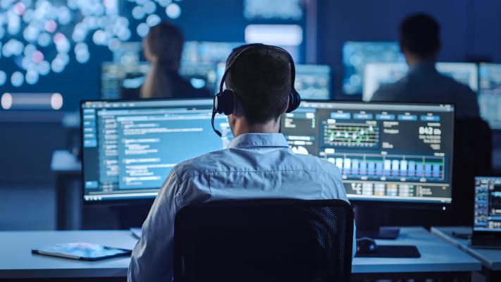 Person sits at desk looking at multiple computer screens