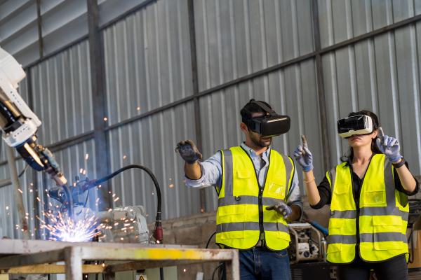 Robotics engineers observe manufacturing robot welding