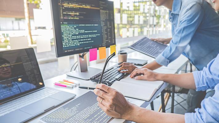 Two software developers huddle at desktop computer