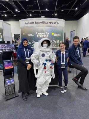 People pose with person in spacesuit at exhibition