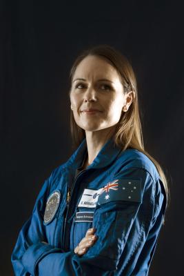 woman in an astronaut uniform smiling.