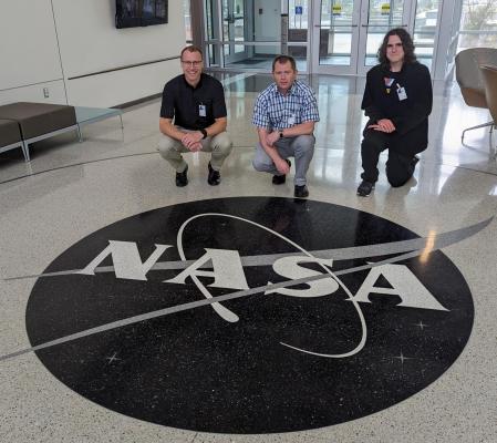 Three posing with a NASA logo