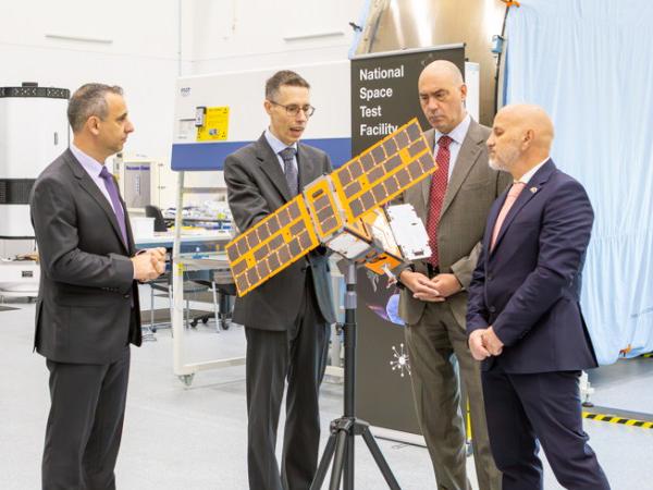 A group of men posing around a satellite.