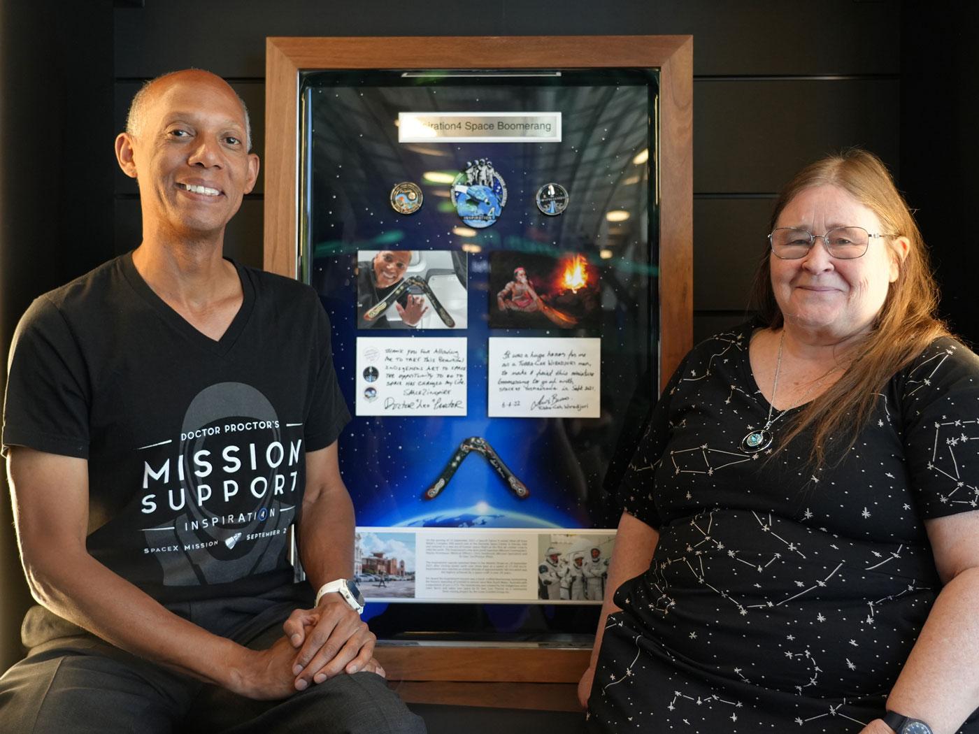 two people posing for a photograph in front of space exhibition