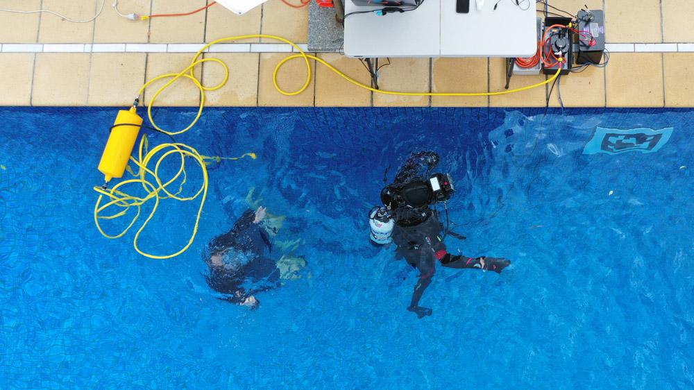 Aerial view of swimming pool used for Titan Lake simulation, with trainees floating in the water and equipment positioned on the side of the pool.